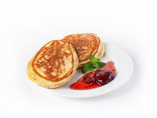 Two large pancakes on a plate with strawberry jam and mint leaves side view