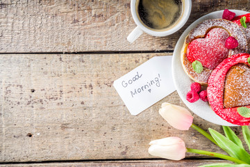 Valentine day brunch food recipe idea. Delicious homemade heart shaped red and white pancakes with berries. Concept of a festive breakfast for Valentine's Day, pleasant surprise for loved one
