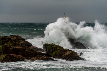 Fototapeta na wymiar Dramatic seascape. Huge waves hit the lighthouse during severe sea storm. 