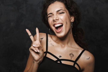 Image of young happy woman winking and gesturing peace sign