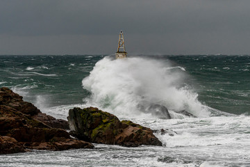 Dramatic seascape. Huge waves hit the lighthouse during severe sea storm. 