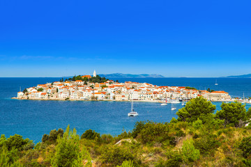 Croatia, panorama of historic town of Primosten on peninsula. Blue bay with sailing boats and yachts. Popular travel destination.