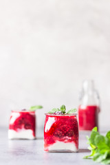 Glass jars of healthy layered berries and yogurt smoothie. Mix berry smoothie with raspberry, blackberry and yogurt. Wellbeing and weight loss concept. Selective focus, toned image.