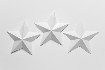Three white hand made origami paper folded stars on white backgound.