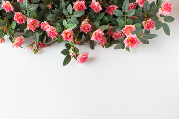 Background with pink artificial roses arranged on top of image. Photo with copy blank space.