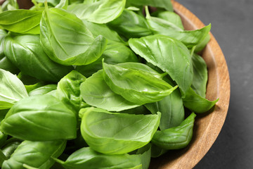 Fresh basil leaves in wooden bowl, closeup