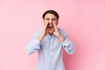 Young caucasian man posing in a pink background isolated shouting excited to front.