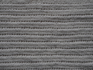 Knitted fabric texture. Gray. Simple knitting with front and back loops. Knitting on the knitting needles. Horizontal lines.