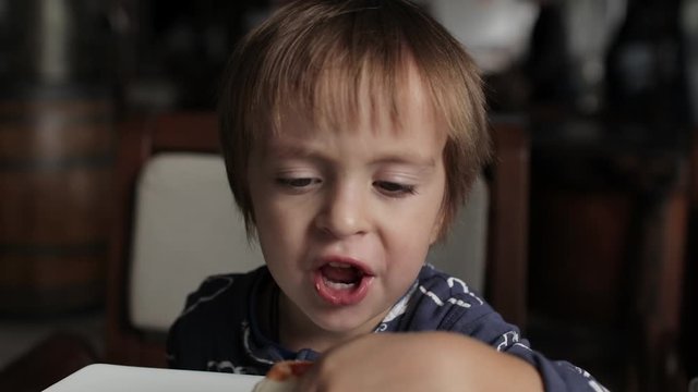 Close up of little cute boy eating pizza. Neutral colors for collor correction.