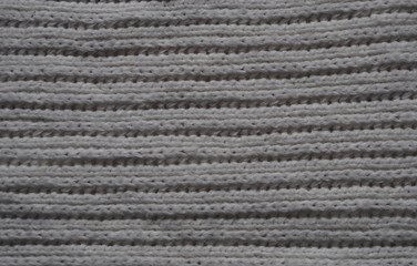 Knitted fabric texture. Gray. Simple knitting with front and back loops. Knitting on the knitting needles. Horizontal lines.
