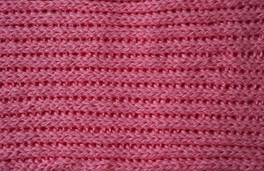 Knitted fabric texture. Pink color. English knitting with front and back loops. Knitting on the knitting needles. Horizontal lines.