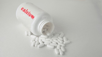 calcium in tablets, closeup white pills scattered on the table