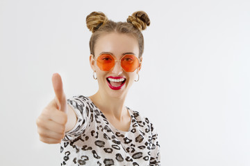 Close-up woman face. Fashion female closeup in trendy clothes isolated on white background. Summer fun time and summertime accessories. Funny girl. Big thumb up. Selective focus