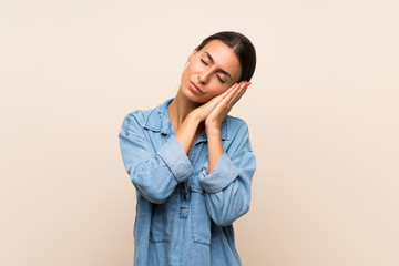 Young woman over isolated background making sleep gesture in dorable expression