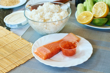 Homemade sushi rolls preparation. Traditional ingredients products foodstuff on the home kitchen table ready to be prepared. Asian food background.
