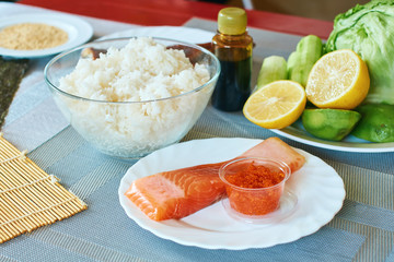 Homemade sushi rolls preparation. Traditional ingredients products foodstuff on the home kitchen table ready to be prepared. Asian food background.
