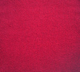 Knitted fabric texture. Red color. Garter stitch with facial loops. Knitting on the knitting needles. Knitted background.