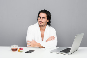 Young handsome man working after a shower frowning face in displeasure, keeps arms folded.