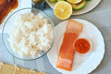 Homemade sushi rolls preparation. Traditional ingredients products foodstuff on the home kitchen table ready to be prepared. Asian food background. Top view.