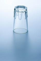 Clear water glass placed upside down on a bright background.