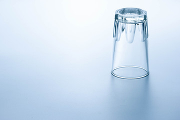 Clear water glass placed upside down on a bright background.