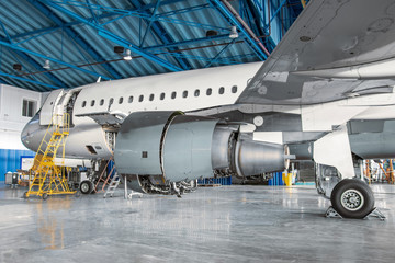 Fototapeta na wymiar Narrow-body passenger aircraft for maintenance in the hangar, side view of the engine and landing gear.