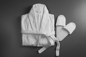 Clean folded bathrobe and slippers on grey background, flat lay