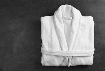 Clean folded bathrobe on black stone background, top view