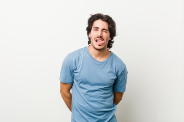 Young handsome man against a white background funny and friendly sticking out tongue.