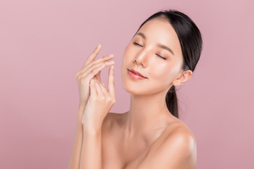 Young happy beautiful Asian woman eyes closed and smiling holding her hand gentle, hand skin care concept, isolated on pink.