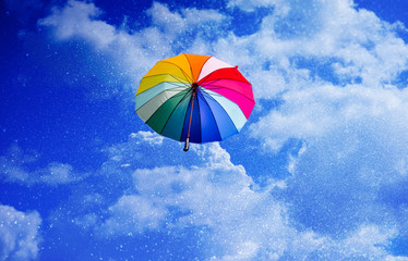 Multicolored umbrella flying suspended over bright blue sky background , with copy space.