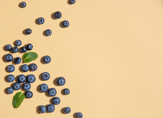 pattern of fresh  blueberries and mint leaves  is laid out on a yellow background