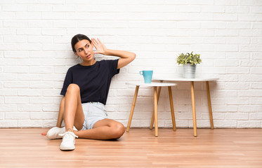 Young woman sitting on the floor listening something