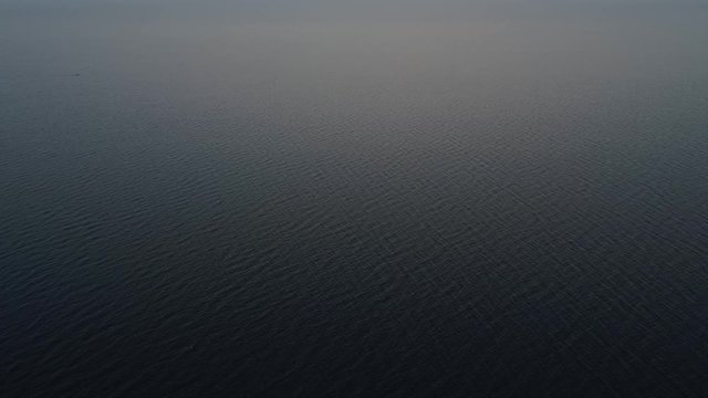 Aerial video of endless, blue, empty sea or ocean water surface at sunset. Shot from high altitude. 