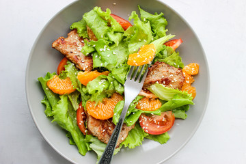 Salad with sweet tangerines and pieces of pork