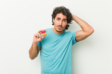 Young man holding macaroons being shocked, she has remembered important meeting.