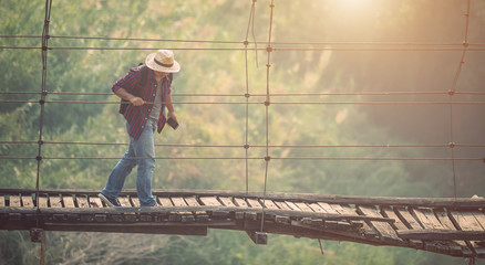 Asian tourist man walking on the old and broken wood bridge