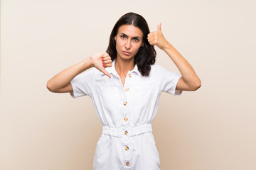 Young woman over isolated background making good-bad sign. Undecided between yes or not