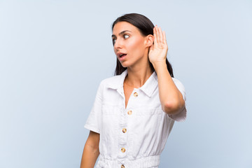 Young woman over isolated blue background listening something