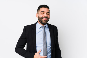 Young latin business woman against a white background isolated touches tummy, smiles gently, eating and satisfaction concept.