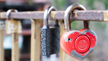 Shabby red lock in the shape of a heart. Valentine's day love concept. A padlock hanging on a metal railing is a sign of eternal love. The tradition of hooking a castle with a fence