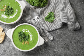 Tasty kale soup served on grey table, flat lay