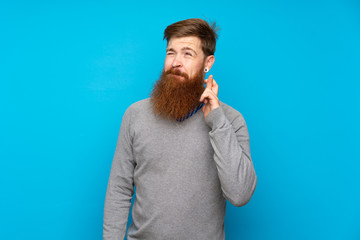 Redhead man with long beard over isolated blue background with fingers crossing and wishing the best