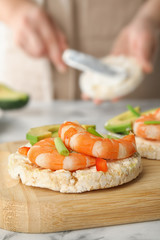 Puffed rice cake with shrimps and avocado on wooden board, closeup