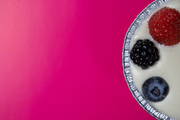 Cheesecake with berries on a pink background