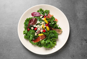 Tasty fresh kale salad on grey table, top view