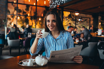 woman drinking tea and reading newspapers in cafe
