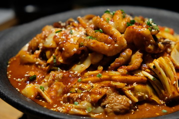 Close up Octopus and pickled pork in black pot. Popular Korean cuisine. Blur background
