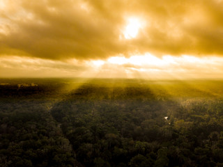 Aerial view of sunbeams shining through clouds onto forest in northern Florida.