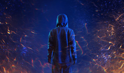 Fototapeta premium Widok z tyłu hakera w bluzie z kapturem. Niebezpieczny haker z kapturem. Internet, cyberprzestępczość, cyberatak, łamanie systemu i koncepcja złośliwego oprogramowania. Anonimowy. Ciemne tło, flary ognia.